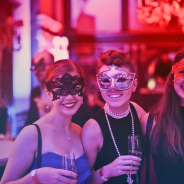 Three women wearing masks and holding glasses